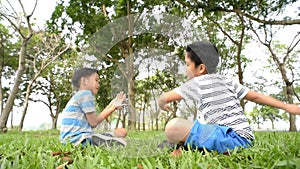 Preteen Asian boy sit and play on a grass