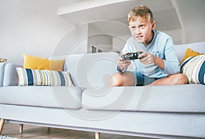 Preteen boy enthusiastically plays the game console
