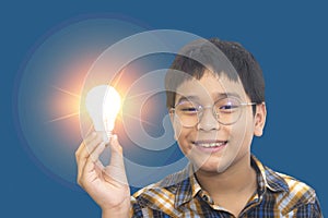 Preteen boy holding glowing light bulb lamp in hand, looking at camera with smile. creativity, thinking out of the box, idea and