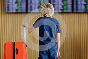 Preteen boy is in international airport or on railway station platform looking on information display of timetable. Check-in.