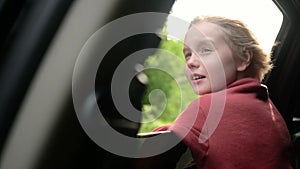 Preteen boy look out through window of car during family road trip and enjoy of pleasant expectation of happy vacation