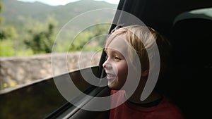 Preteen boy look out through window of car during family road trip and enjoy of pleasant expectation of happy vacation