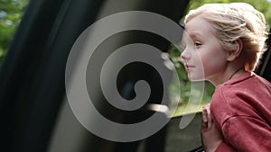 Preteen boy look out through window of car during family road trip and enjoy of pleasant expectation of happy vacation