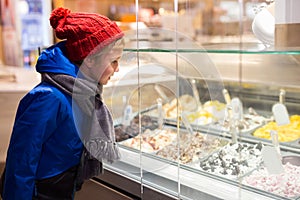 Preteen boy looking at ice cream in showcase outdoors