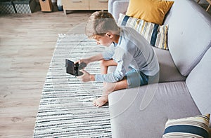 Preteen boy losted in computer game. Sits at home on coze sofa photo