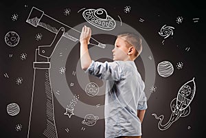 preteen boy pretending to be a astronomer with drawn telescope and UFO, planets, spaceship photo