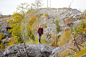 Preteen boy in red shirt is exploring nature and having fun during hiking in mountains valley on sunny day. Active leisure for