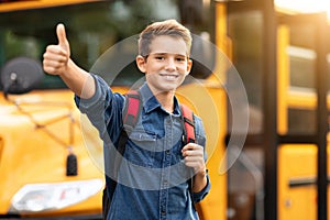 Preteen Boy Showing Thumb Up At Camera While Standing Near School Bus