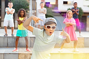 Preteen boy in sunglasses dancing krump with tweens on city street