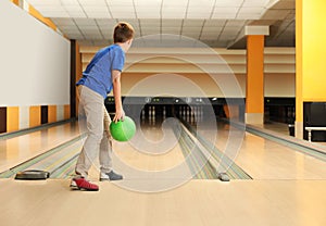 Preteen boy throwing ball at bowling. Space for text