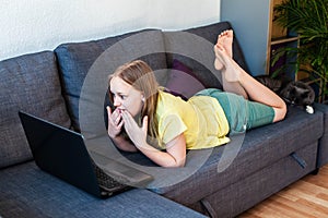 Preteen caucasian girl with amazed look chatting online using laptop for video call.