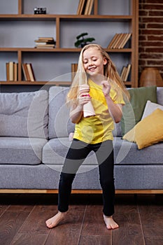 Preteen child singing into microphone and dance at home, entertainment and education concept, indoor