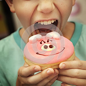 Preteen by eat doughnut with pig glaze close up