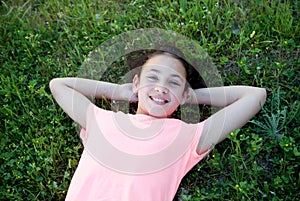 Preteen girl with blue eyes lying on the grass