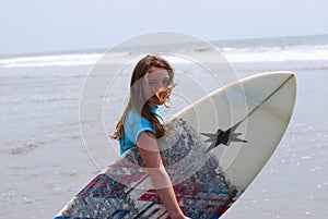 Preteen girl carrying a surfboard to the ocean