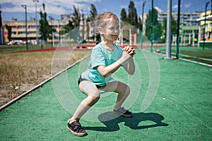 Preteen girl making exercises with fitness resistance band at public sportsground in city, sport