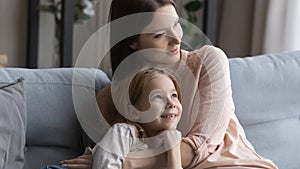 Preteen girl relax on sofa snuggle up to caring mother