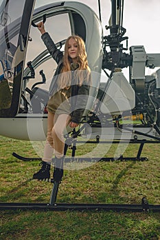 Preteen girl standing on footboard of open helicopter