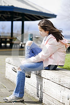 Preteen girl tying shoes outdoors