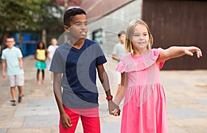 Preteen girl walking with african american friend along city street