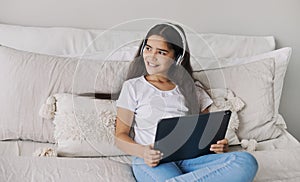 Preteen girl wear headphones using modern digital tablet at home