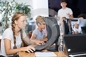 Preteen girl working with computer programs in training room