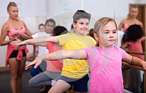 Preteen girl working near ballet barre during group class