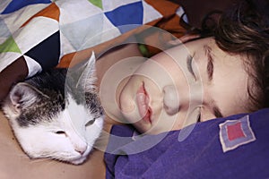 Preteen handsome boy with cat sleeping