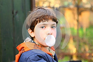 Preteen handsome boy with chewing gum bubble close up counrty po photo