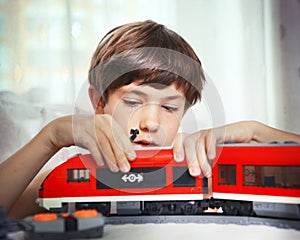 Preteen handsome boy play with meccano toy train and railway sta