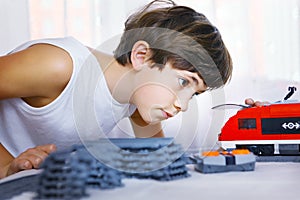 Preteen handsome boy play with meccano toy train and railway sta photo