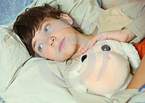 Preteen handsome boy sick in bed with toy