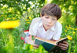 Preteen handsome keen boy red and old book in the summer park wi