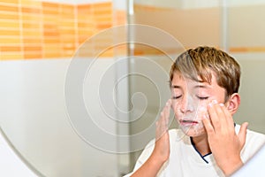 Preteen massages her face with cream with her eyes closed