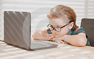 Preteen schoolboy doing her homework with laptop at home. Online education concept, home schooler pupil.