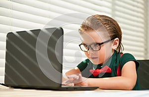 Preteen schoolboy doing her homework with laptop at home. Online education concept, home schooler pupil.