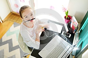 Preteen schoolgirl doing her homework with laptop computer at home. Child using gadgets to study. Online education and distance