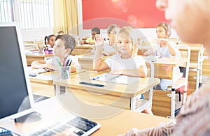 Preteen schoolgirl raising hand to answer during lesson