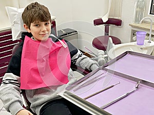 Preteen young boy visiting dentist, having his teeth checked by dentist in dental office. Happy teenager without fear.