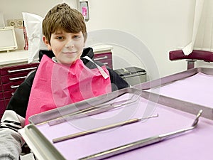 Preteen young boy visiting dentist, having his teeth checked by dentist in dental office. Happy teenager without fear.