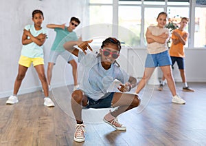 Preteenage boy and girl in sunglasses dancer practicing active dance in modern studio