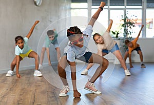 Preteenage boy and girl in sunglasses dancer practicing active dance in modern studio