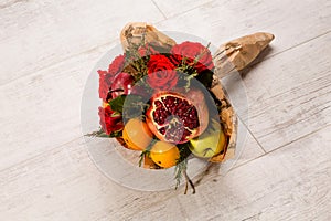 Prettily wrapped composition of red roses and fruits.