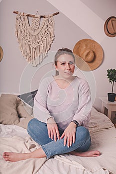 Pretty 25-year-old girl at home on  bed in  sweater and jeans