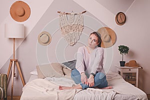 Pretty 25-year-old girl at home on  bed in  sweater and jeans