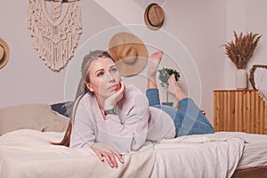 Pretty 25-year-old girl at home on  bed in  sweater and jeans