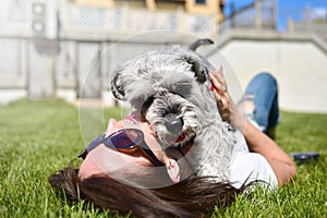 Pretty adult caucasian happy woman resting in the park on a sunny day with her beloved dog. Female lies on the grass, smiling and