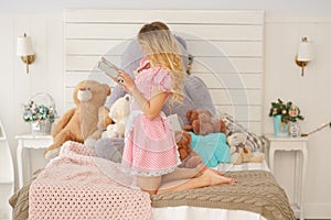 Pretty adult girl with her secret diary in her white bedroom with many plush teddy bears