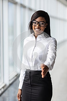 A pretty african american business woman offering a handshake in office