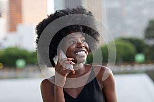 A pretty African american business woman talking on a cell phone at office building in the city